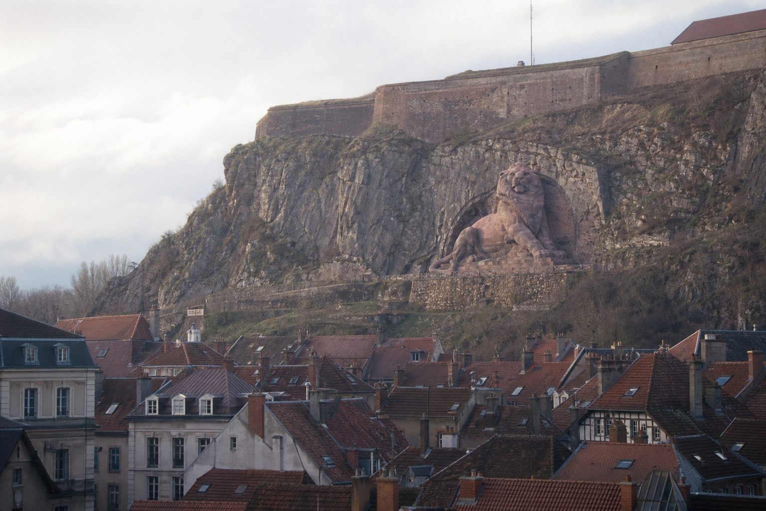 The Lion of Belfort carved in red sandstone on the rock of the citadel, above the old town rooftops